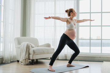 Pregnancy yoga fitness workout training. Pregnant woman practicing yoga at home. Pregnant girl doing sports exercise on yoga mat indoor. Woman with big belly have fitness training practicing asana