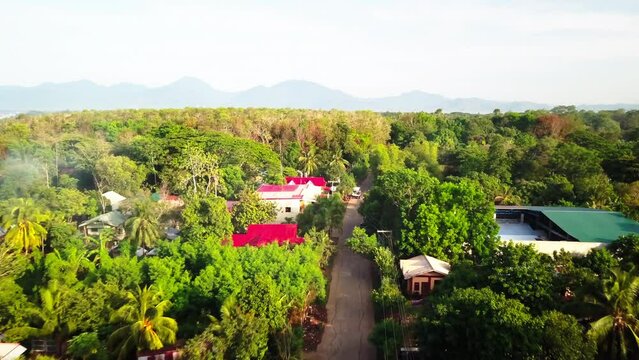 Aerial Forward Beautiful Shot Of Road Amidst Green Trees By Mountains Against Clear Sky - Puerto Princesa, Philippines