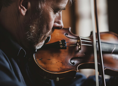 Close-up of focused man playing violin, instrument details visible