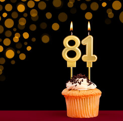 Birthday candle with cupcake - Number 81 on black background with out of focus lights