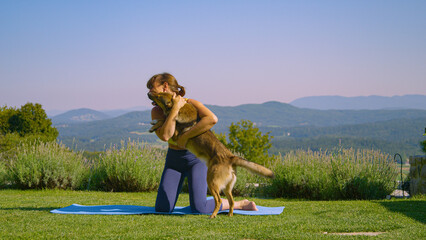 Excited young dog jumps and hugs a lady practicing crescent lunge yoga pose