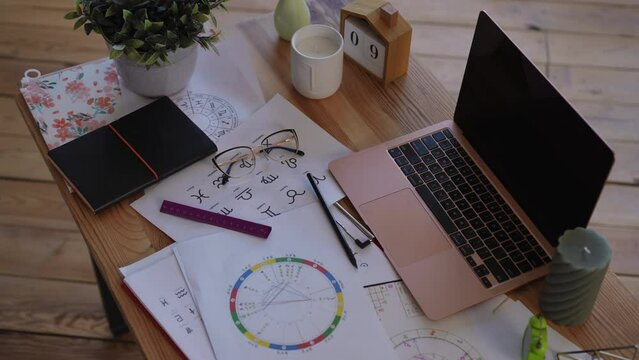 Top view. Workplace of a modern businesswoman. A laptop, a natal chart, candles and a houseplant, everything for comfortable and harmonious work in a modern office
