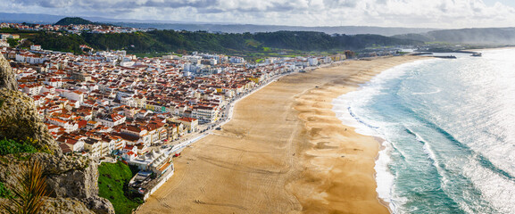 Overlooking the sweeping curve of Nazare's shoreline, where the sun kisses the Atlantic. Pano - 786721183