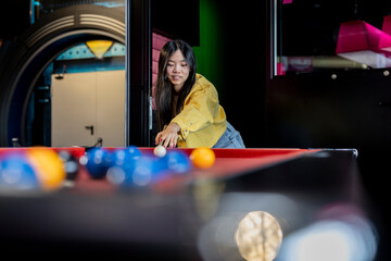 Asian teenage woman playing billiards