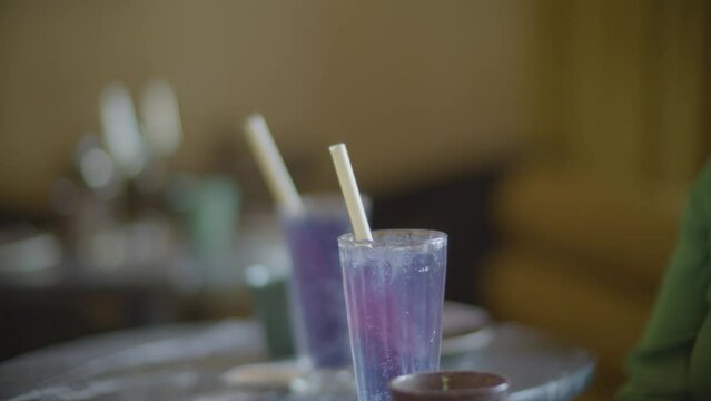 mano preparando una bebida morada en vasos