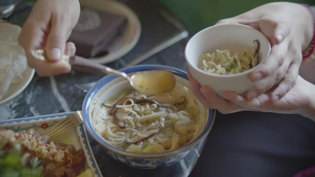 manos de mujer sirviendo sopa asi&aacute;tica