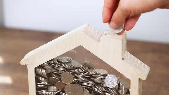 saving coins in a house-shaped piggy bank