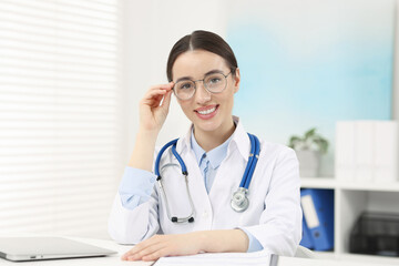 Medical consultant with glasses and stethoscope at table in clinic
