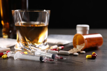 Alcohol and drug addiction. Syringes, whiskey in glass and pills on grey table, closeup