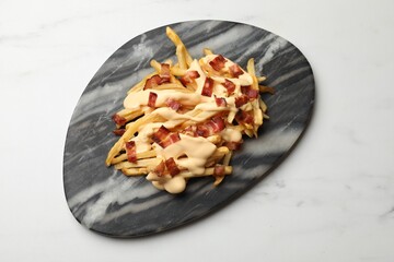 Delicious French fries with bacon and cheese sauce on white marble table, top view