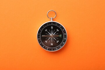 One compass on orange background, top view. Tourist equipment