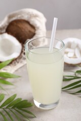 Glass of coconut water, palm leaves and nuts on light table