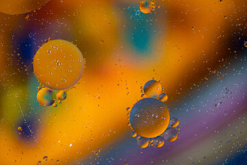 Macro photography of yellow oil bubbles dissolved in water. Colorful background.