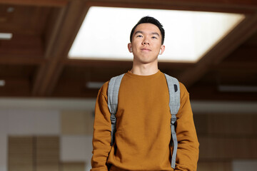 A college student wearing earphones walking in a classroom