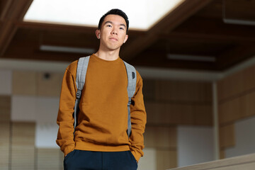 A college student wearing earphones walking in a classroom
