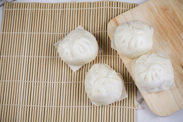 Steamed buns with minced pork on bamboo cutting board. Chinese food dim sum style. Breakfast Asian food.