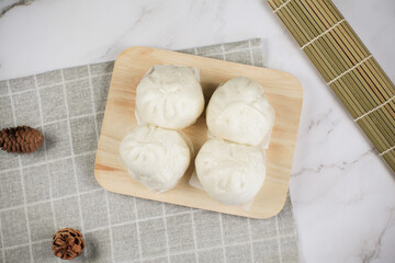 Steamed buns with minced pork on bamboo cutting board. Chinese food dim sum style. Breakfast Asian food.