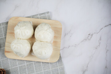 Steamed buns with minced pork on bamboo cutting board. Chinese food dim sum style. Breakfast Asian food.
