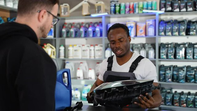 African american seller gives the buyer new automotive headlight