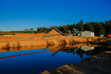 Sand mining.Industrial equipment for sand mining. Equipment for extracting sand is situated on the shore of a pond , surrounded by a pine forest. Sand quarry. - 786743188