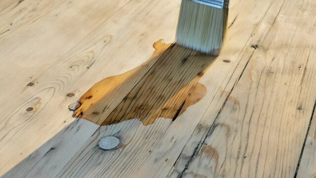 Oil for wood. brush applies oil to a wooden table. impregnation of wooden boards with oil is a process used to enhance the durability and resistance of wood against environmental factors. 4k footage