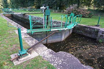 Fototapeta na wymiar A canal lock on the Oust River in Josselin, France is part of the important Nantes-Brest Canal system that crosses Brittany with a wide network of waterways to connect with the Atlantic Ocean.