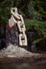A chain is carved from a tree stump with saw dust on the ground. The scene is peaceful and serene. - 786750109