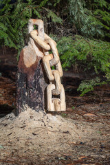 A chain is carved from a tree stump with saw dust on the ground. The scene is peaceful and serene. - 786750121