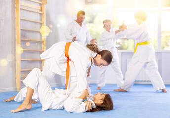 Two girls judokas practice judo technique in group in gym