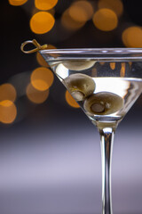 A martini glass with olives in it. The olives are marinating inside of the drink and the glass is full