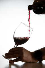 Action shot pouring red wine into a glass over a white background