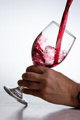 Action shot pouring red wine into a glass over a white background - 786753387