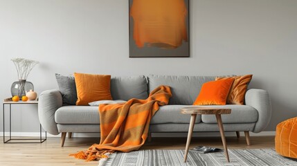 Orange blanket on grey sofa in modern apartment interior with poster and wooden table