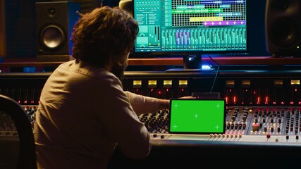 Audio technician working with music recording software and editing tunes, mixing console and...