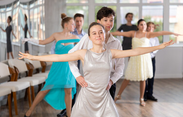 Emotional adolescent ballroom dancers, girls and boys in formal wear practicing elegant dance moves...