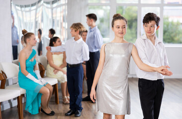 Group of young couple of teenagers in evening dresses dance an polonaise dance