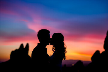 Silhouette of a couple sharing a kiss against a colorful sunset