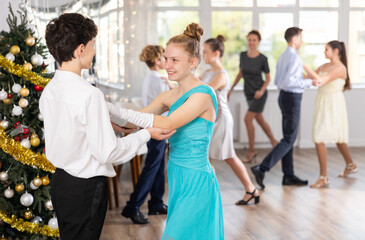 Smiling teenage girl enjoying slow dance with friend at school event during festive Christmas party...