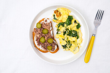 Omelet with spinach leaves with tuna sandwich and cream cheese and salt cucumber.Omelette on plate, scrambled eggs on white background, top view.