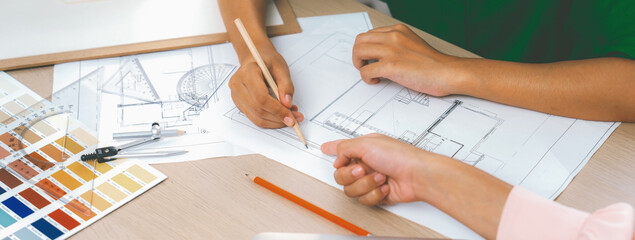 Professional architect drafts blueprint from project manager advice on table with house model,...