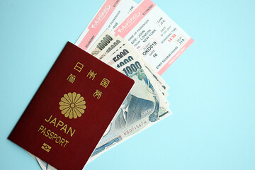 Japan passport with money and airline tickets on blue background close up. Tourism and travel concept