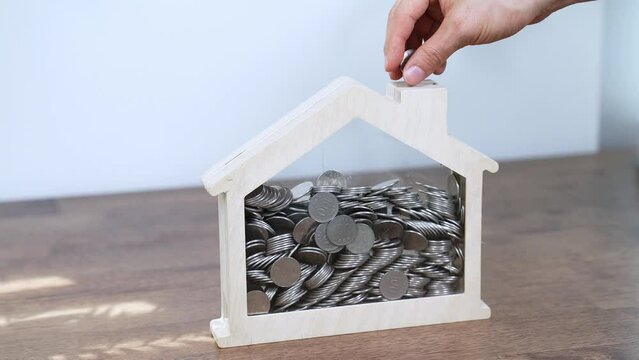 saving coins in a house-shaped piggy bank