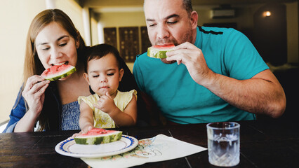 Latin family eating at home. Father, mother and baby daughter dining together. Family concept