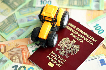 Red polish passport and yellow tractor on euro money bills close up