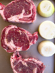 Raw Ribeye Steaks Seasoned with Spices and Onion Halves on Tray - 786770905