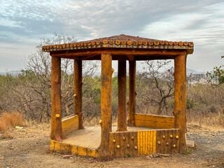 A wooden pavilion with a roof and pillars at Ralamandal, Indore, India.