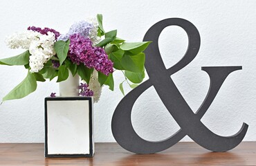 wooden figurine ampersand symbol and lilac in a vase on a wooden chest of drawers
