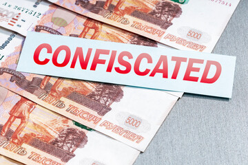 Russian ruble money and list with word CONFISCATED. Arrest, confiscation of financial assrts of...