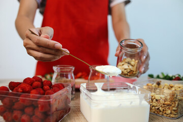 Hand Making Strawberry Parfait Dessert at The Kitchen, Adding Yoghurt into The Jar. 