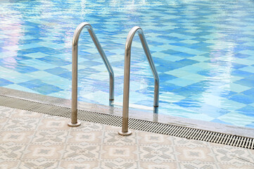 Grab bars ladder in the blue swimming pool, selective focus for convenience and relaxation in luxury condos in Thailand - obrazy, fototapety, plakaty